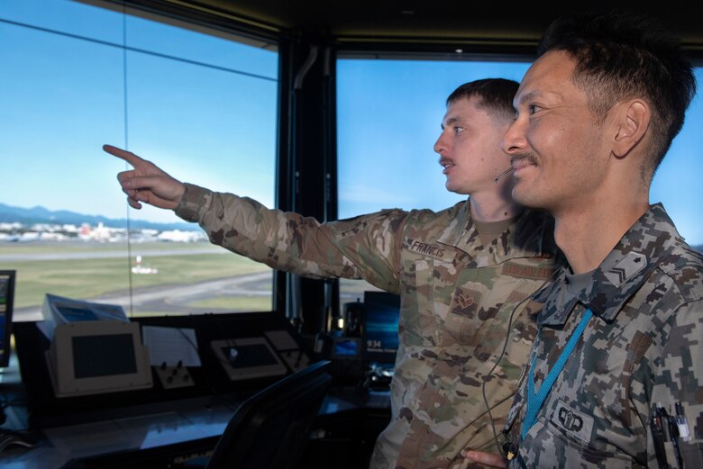 Senior Airman Kenyan Francis, 374th Operations Support Squadron air traffic controller, explains how they direct air traffic to Koku-Jieitai Tech. Sgt. Shinichi Ishimoto, Air Traffic Control Group air traffic controller assigned with Komatsu Air Base, Japan, during a Bilateral Exchange Program, Oct. 23, 2019, at Yokota Air Base.