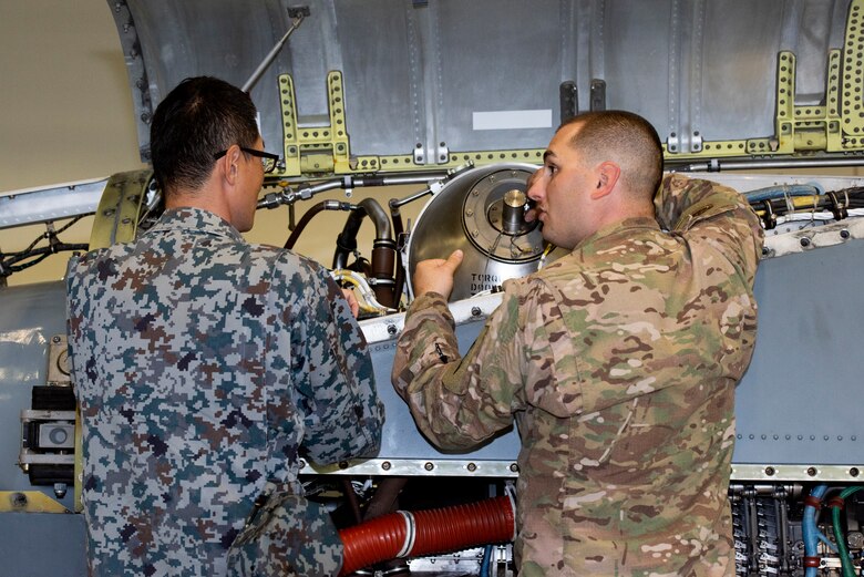 Tech. Sgt. Andrew Maskrey, 374th Aircraft Maintenance Squadron NCO in charge of C130J Super Hercules engines, explains how an engine operate to Koku-Jieitai Staff Sgt. Koji Yamaguchi, 1st Air Wing engine maintenance assigned with Hamamatsu Air Base, Japan, during a Bilateral Exchange Program, Oct. 24, 2019, at Yokota Air Base.