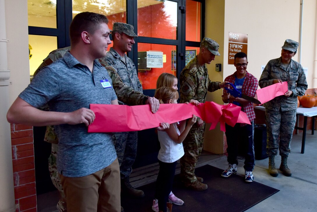 Wing leadership, Wyvern Refuge council members, and guests cut the ribbon during the Wyvern Refuge re-opening ceremony at Aviano Air Base, Italy, Oct. 25, 2019. The Refuge recently went through more than $17,000 worth of renovation, aimed towards offering Airmen E1 through E4 a place to meet and relax on base. (U.S. Air Force photo by Staff Sgt. Kelsey Tucker)