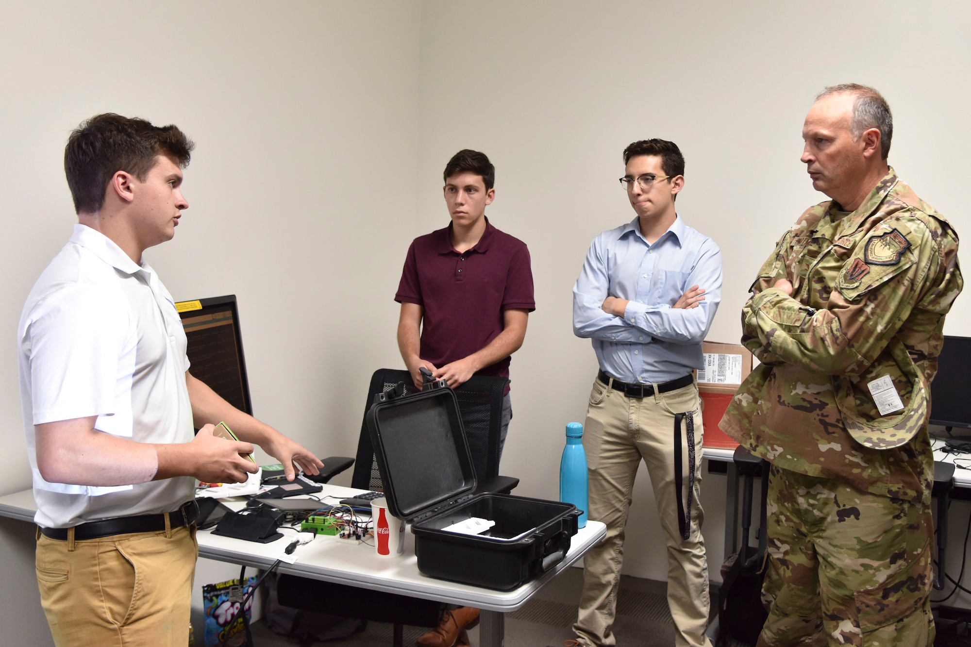 Matthew Santalla, a senior at Florida Polytechnic University majoring in Business Analytics and Quantitative Economics, briefs Col. Chad Hartman, commander of the Air Force Technical Applications Center, on a system he and four other university students developed during their X-Force summer fellowship with the nuclear treaty monitoring center at Cape Canaveral Air Force Station, Fla.  The program is sponsored by the National Security Innovation Network.  Pictured left to right:  Santalla; Andrew Bass, a freshman at Washington University in St. Louis;  Bryan Urias, a senior at Florida Polytechnic University; and Hartman. (U.S. Air Force photo by Matthew S. Jurgens)