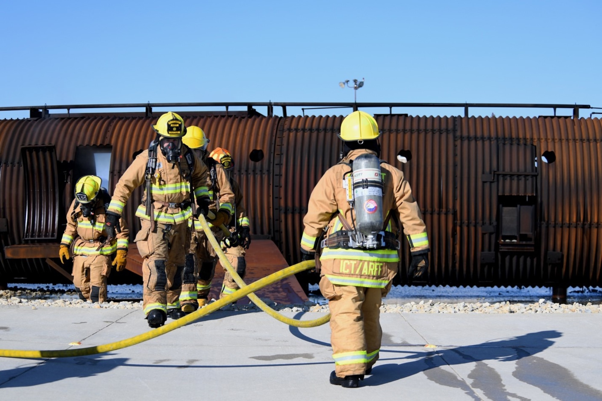Firefighters from the Wichita Airport Police and Fire Department depart the training aircraft after putting out an interior fire Oct. 21, 2019, at McConnell Air Force Base, Kan. The fires were controlled by an individual in a tower that moderated the distribution of liquid propane through an electronic control system. The liquid propane was then ignited by spark plugs embedded throughout the training aircraft. (U.S. Air Force photo by Airman 1st Class Nilsa E. Garcia)