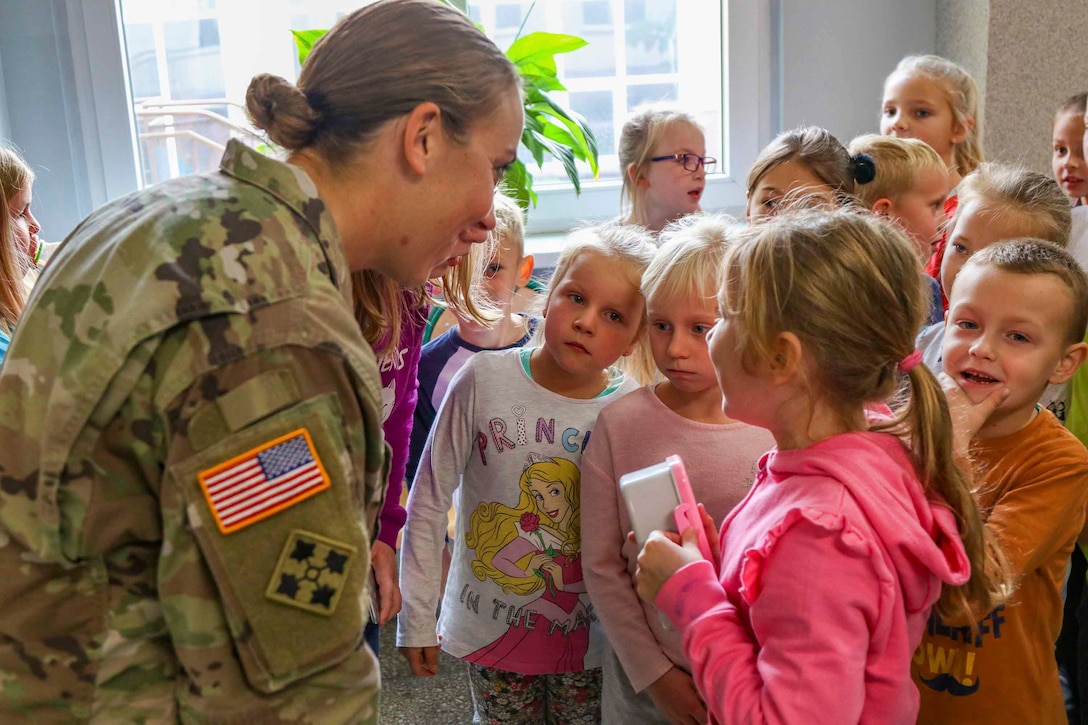 A soldier speaks to a group of young students.