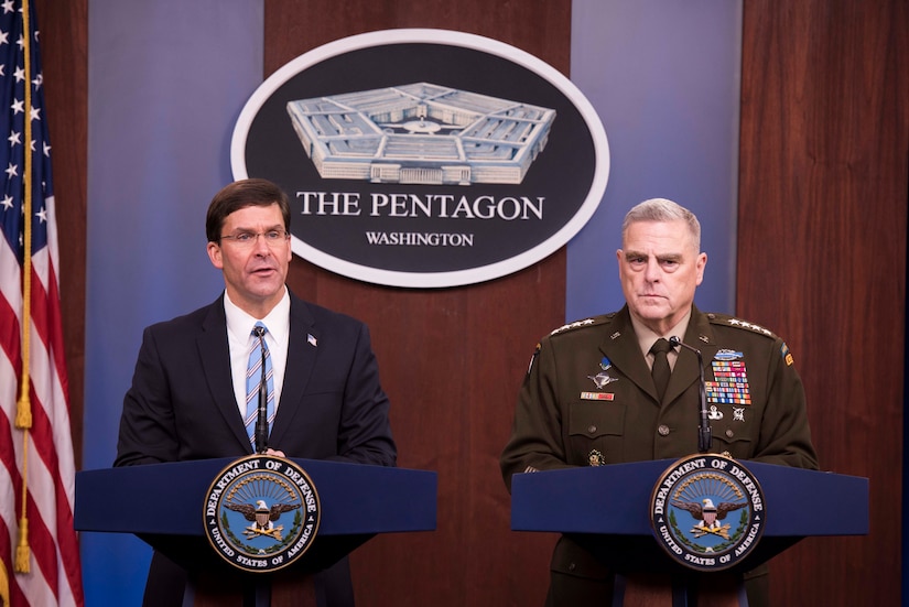 Man in suit and man in uniform stand at identical lecterns. The lecterns bear Department of Defense emblems, and behind them is a Pentagon emblem.
