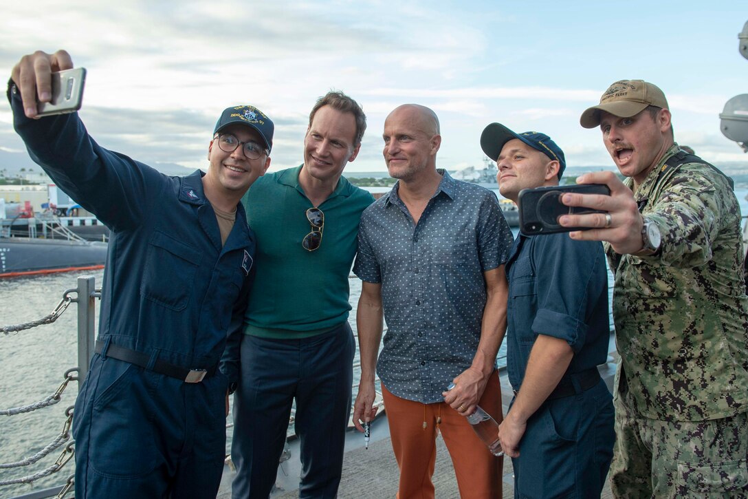 Actors Patrick Wilson and Woody Harrelson pose on the deck of a ship to get selfies with three sailors.