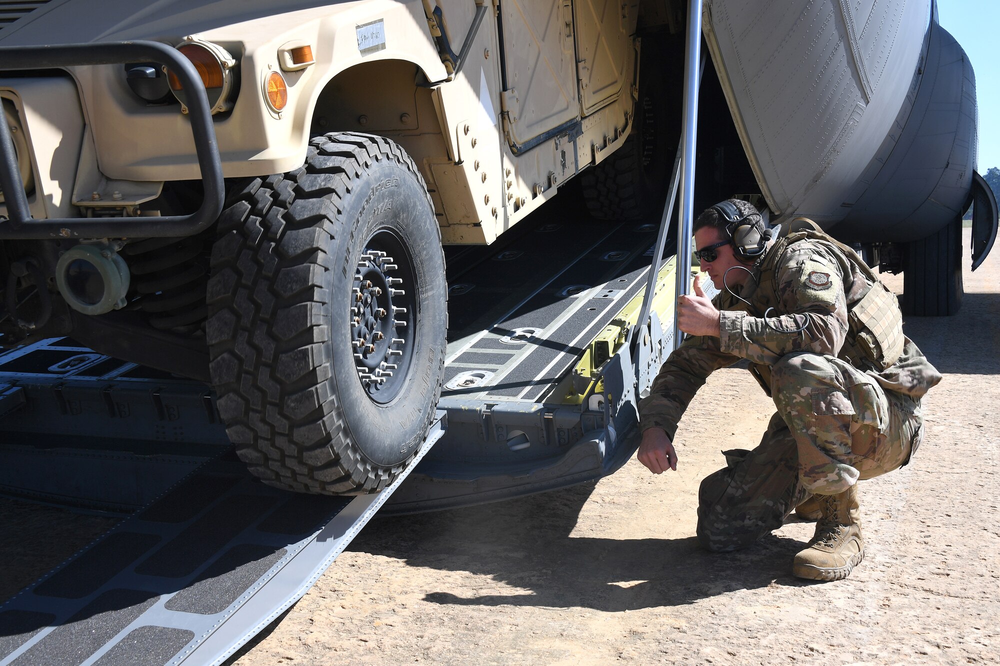 U.S. Air Force Staff Sgt. Christopher Hayes, 621st Contingency Response Support Squadron aircraft maintenance, checks aircraft clearance while loading cargo inside a C-130 Hercules aircraft at the Geronimo Landing Zone during exercise Green Flag Little Rock, Oct. 23, 2019, Fort Polk, Louisiana. During the exercise the team loaded and downloaded tactical vehicles, airdrop bundles, along with a variety of other pallets to support the Army. (U.S. Air Force photo by Tech. Sgt. Liliana Moreno)