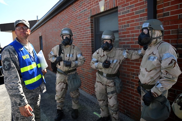 At left, 932nd Airlift Wing's Mission Support Group Wing Inspection Team (WIT) member, Senior Master Sgt. Michael Atkins, listens to instructions from another team member.  He observed  as the civil engineers in protective gear prepared to move to another area during a Full Scale Readiness Exercise held during a reserve Unit Training Assembly weekend at Scott Air Force Base, Ill.  Reservists from multiple states came together Sept. 7-8 to train and strengthen their Ability to Survive and Operate skills.   (U.S. Air Force photo by Lt. Col. Stan Paregien)