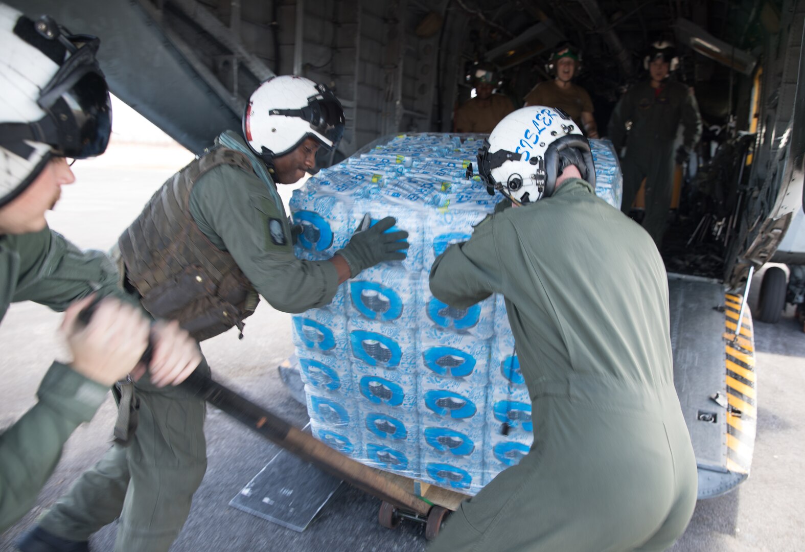 Service members remove a pallet of water from the back of an aircraft.