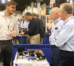 Alec Fixl, far left, DLA Troop Support Industrial Hardware employee speaks to vendors at the Design-2-Part Show Oct. 23-24 in Oaks, Pennsylvania.
