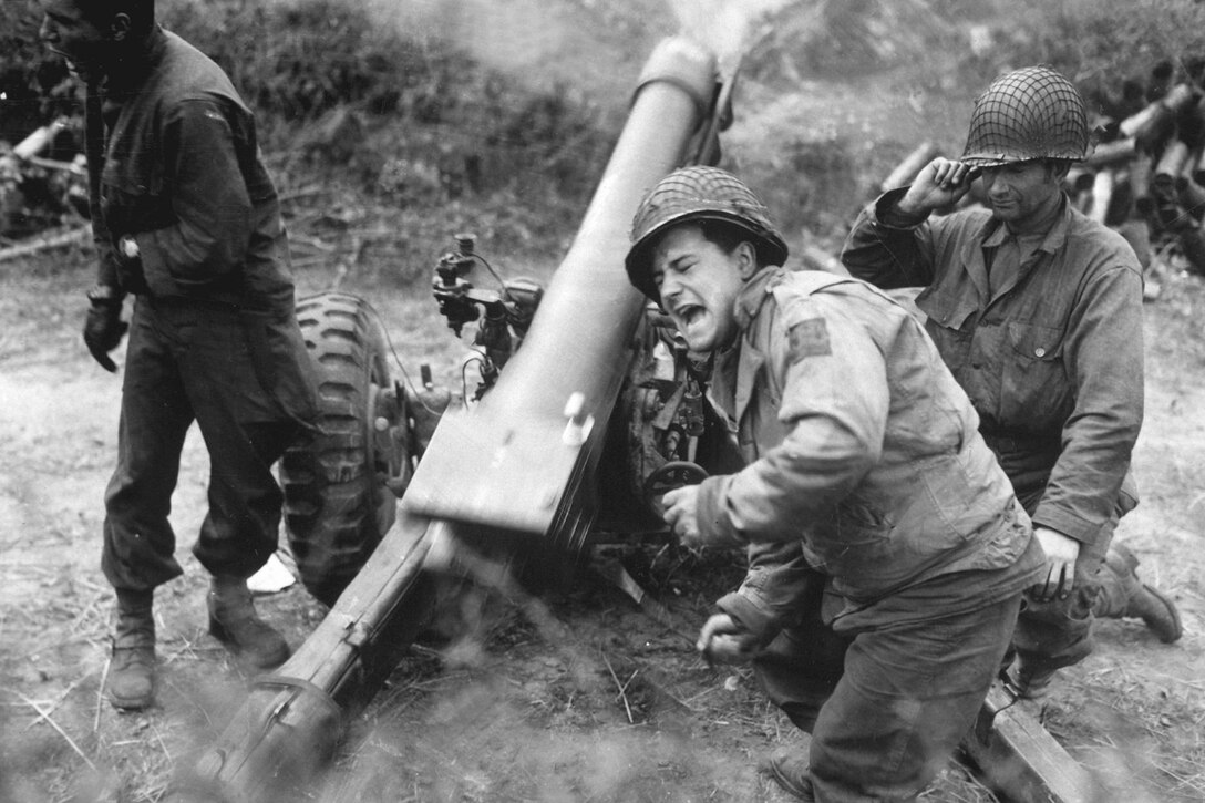 A soldier grimaces while firing an artillery piece.