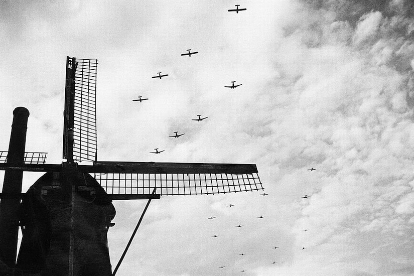 Aircraft fly over a windmill.