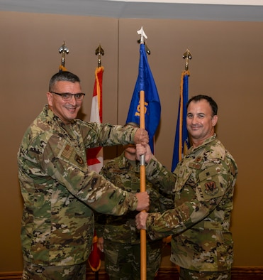 Col. Michael Valle, Assistant Adjutant General-Air and Florida Air National Guard commander, passes the ceremonial flag to Col. Matthew Jones, during the 101st Air and Space Group assumption of command ceremony held on the 601st Air Operations Center operations floor at Tyndall Air Force Base, Fla. on Oct. 25, 2019.