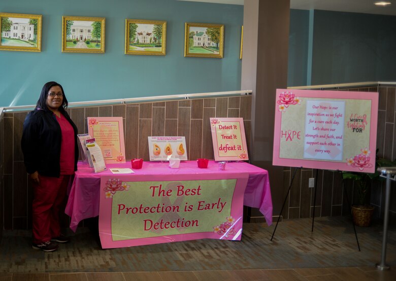 Angela Hamilton, 14th Operational Medical Group Readiness Squadron health management nurse, stands by a Breast Cancer Awareness Month stand at the Koritz Clinic Oct. 22, 2019, on Columbus Air Force Base, Miss. The stand is up for the whole month of October. (U.S. Air Force photo by Airman Davis Donaldson)