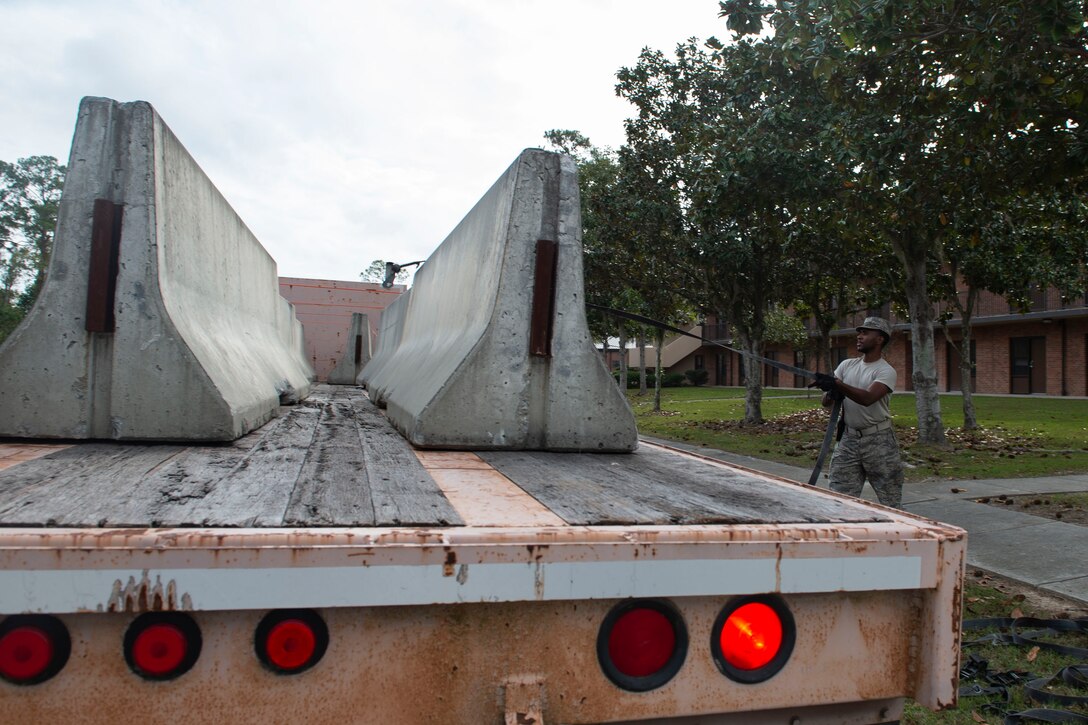 Airman 1st Class Tyrek Dozier, 23d Logistics Readiness Squadron (LRS) ground transportation operator, removes a securing strap from cement barriers Oct. 25, 2019, at Moody Air Force Base, Ga. The 23d LRS Airmen used cement barriers to close off the HC-130J Combat King II ramp for air show parking and to protect Moody’s assets and personnel. (U.S. Air Force photo by Airman Azaria E. Foster)