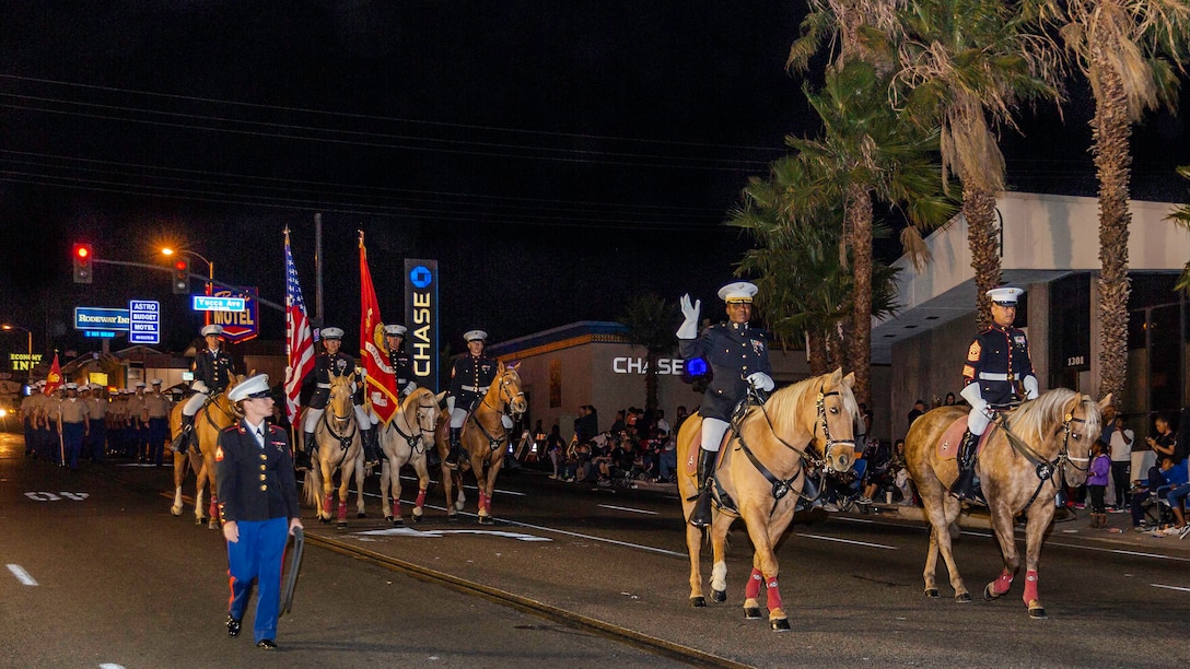 Major Earnest Robinson (middle-right), Headquarters Company Commanding Officer, and 1st Sgt. Enrique De Anda (right), HQCo first sergeant., ride ahead of the Marine Corps Mounted Color Guard and marching Headquarters Company Marines in the Kiwanis Club's 87th annual Mardi Gras Parade in Barstow, Calif., Oct. 26. (U.S. Marine Corps photo by Jack J. Adamyk)