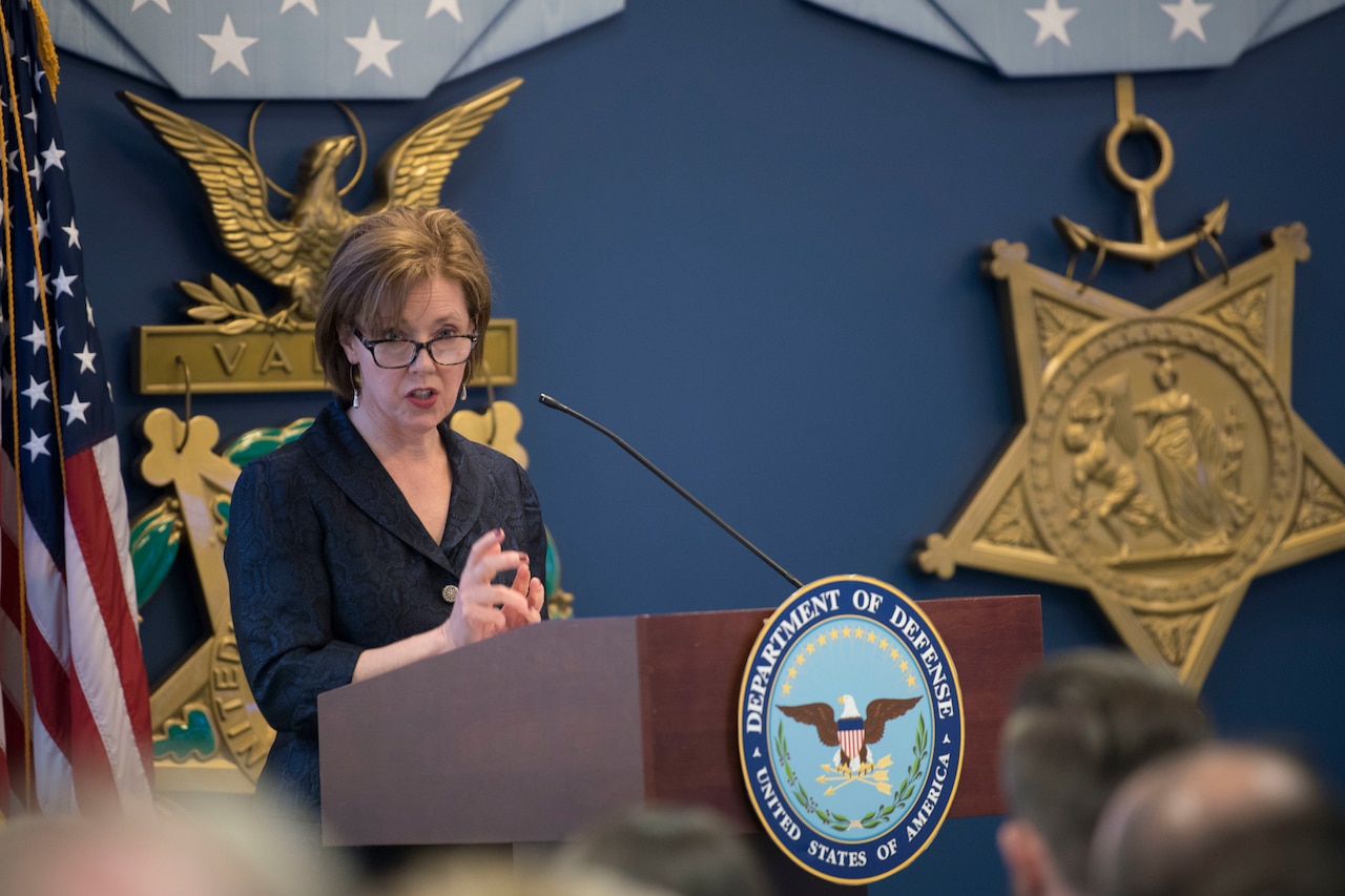 Woman speaks into microphone on podium.