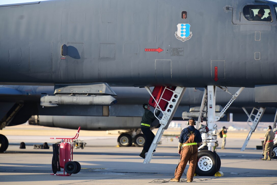 A 28th Bomb Wing maintenance crew chief watches as the crew of a B-1B Lancer loads equipment onto an aircraft before takeoff at Ellsworth Air Force Base, S.D., Oct. 24, 2019.  Several B-1 aircraft flew to the U.S. Central Command area of operations to support a Bomber Task Force. The unannounced arrival of the B-1 demonstrates the global strike capacity and ability of the U.S. Air Force and Air Force Global Strike Command to rapidly deploy forward and deliver precision-guided ordnance against any adversary. Strategic bomber missions enhance the readiness and training necessary to respond to any potential crisis or challenge across the globe. (U.S. Air Force photo by Airman 1st Class John C.B. Ennis)