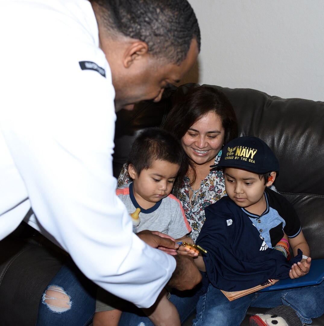 Petty Officer 1st Class Harold Dayse, the leading petty officer assigned to Navy Recruiting Station New Braunfels, presents a Navy Fiesta Medal to Isaac Juarez during a visit by Navy Recruiting District San Antonio Sailors at Isaac’s New Braunfels home Oct. 28.