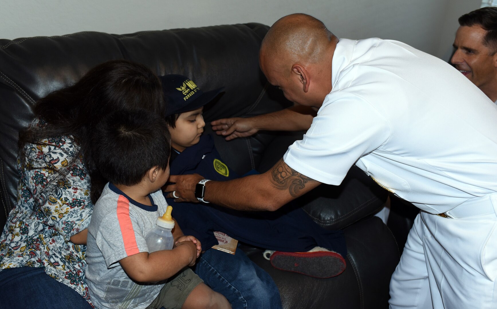 Senior Chief Petty Officer Israel Flores, an officer programs recruiter assigned to Navy Recruiting District San Antonio, presents a Forged by The Sea T-shirt to Isaac Juarez during a visit by NRD Sailors at Isaac’s New Braunfels home Oct. 28. Isaac, 7, who has been diagnosed with terminal cancer, was presented with an Honorary Sailor Certificate, an America’s Navy ball cap, a Navy Fiesta Medal, and a copy of the U.S. Constitution.