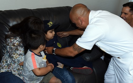 Senior Chief Petty Officer Israel Flores, an officer programs recruiter assigned to Navy Recruiting District San Antonio, presents a Forged by The Sea T-shirt to Isaac Juarez during a visit by NRD Sailors at Isaac’s New Braunfels home Oct. 28. Isaac, 7, who has been diagnosed with terminal cancer, was presented with an Honorary Sailor Certificate, an America’s Navy ball cap, a Navy Fiesta Medal, and a copy of the U.S. Constitution.