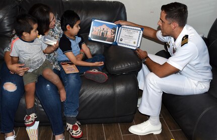 Cmdr. Nicholas Gamiz, Navy Recruiting District San Antonio commanding officer, presents an Honorary Sailor Certificate to Isaac Juarez during a visit by NRD Sailors at Isaac’s New Braunfels home. Isaac, 7, who has been diagnosed with terminal cancer, was also presented with an America’s Navy ball cap, a Forged by The Sea T-shirt, a Navy Fiesta Medal, and a copy of the U.S. Constitution.