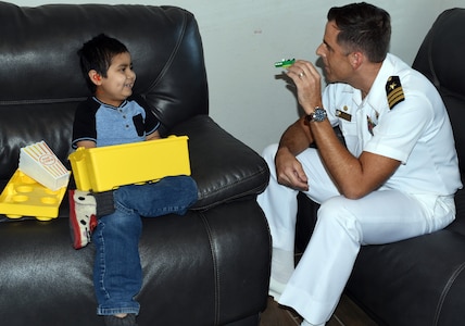 Cmdr. Nicholas Gamiz, Navy Recruiting District San Antonio commanding officer, plays with Isaac Juarez during a visit Oct. 28 by NRD SA Sailors at Isaac’s home. Isaac, 7, who has been diagnosed with terminal cancer, was presented with an Honorary Sailor Certificate, an America’s Navy ball cap, a Forged by The Sea T-shirt, a Navy Fiesta Medal, and a copy of the U.S. Constitution.