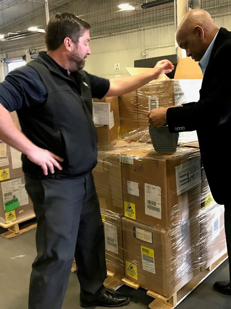 Two men look at a pallet of boxes