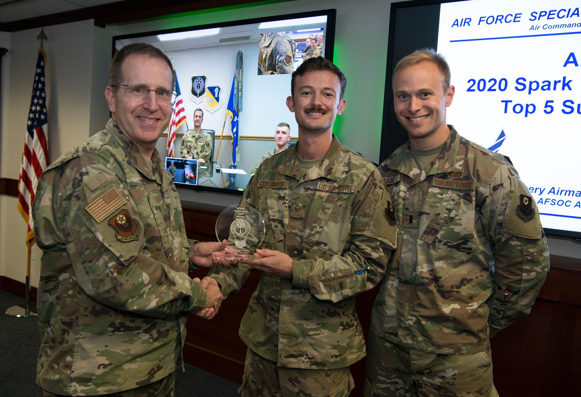Three people holding an award together.