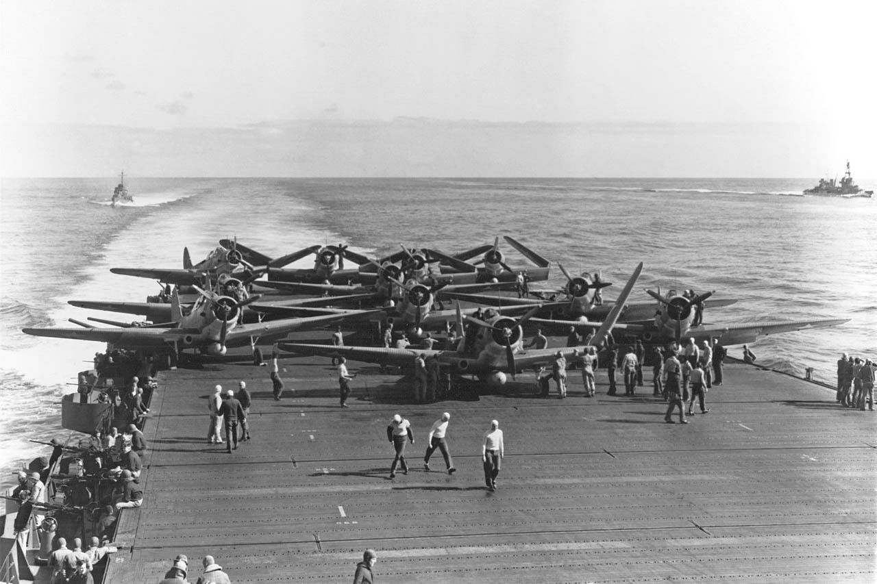Airplanes on the deck of an aircraft carrier in the middle of the Pacific Ocean.