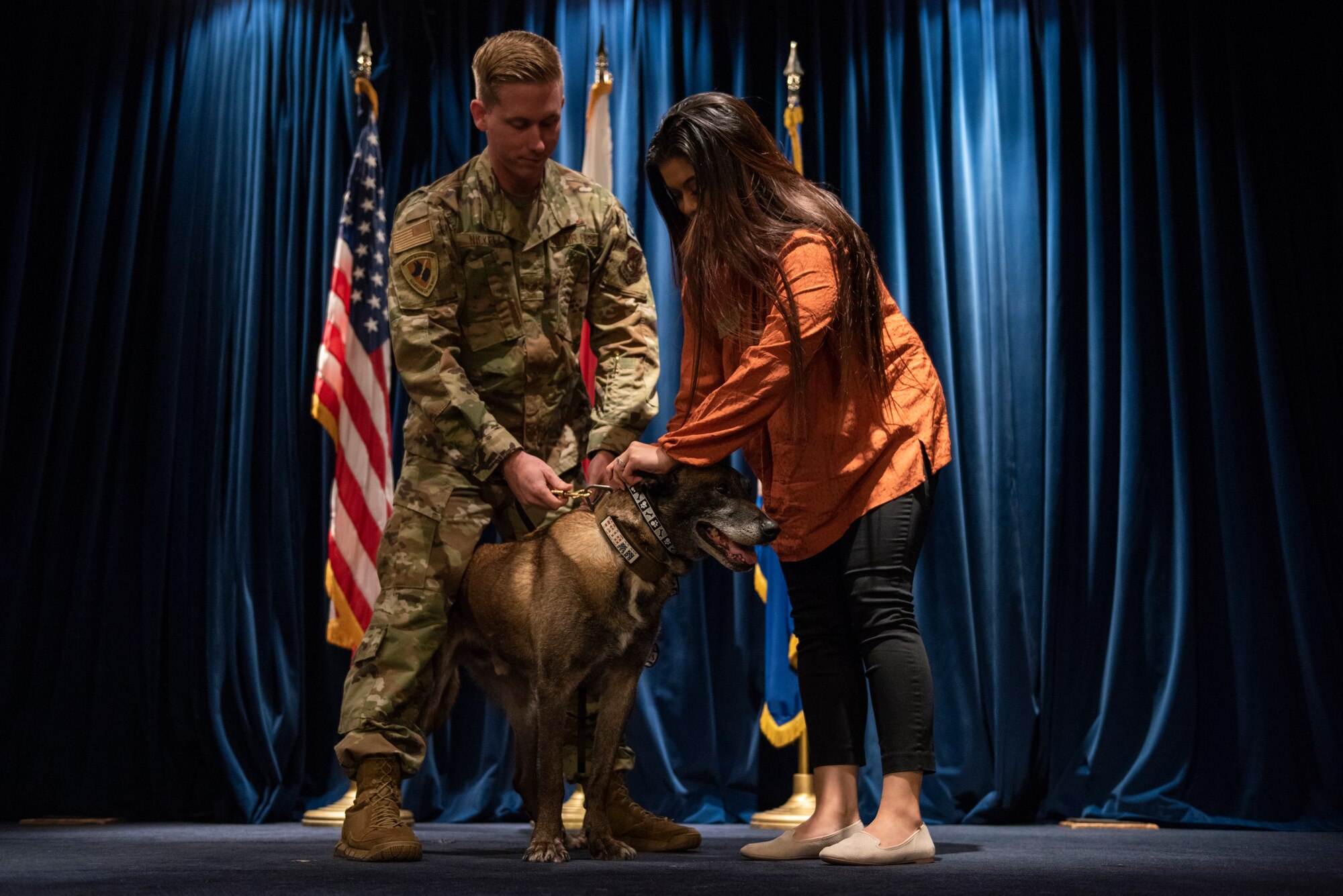 Staff Sgt. Cody Nickell, 374th Security Forces Squadron military working dog handler, and his wife Monikka, perform the ceremonial collar swap signaling the end of military working dog Topa’s service at a retirement ceremony at Yokota Air Base, Japan, Oct. 17, 2019.