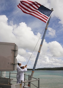 Sailors assigned to the amphibious assault ship USS Boxer (LHD 4) raise the American flag on the fantail after the ship moors at Naval Base Guam.