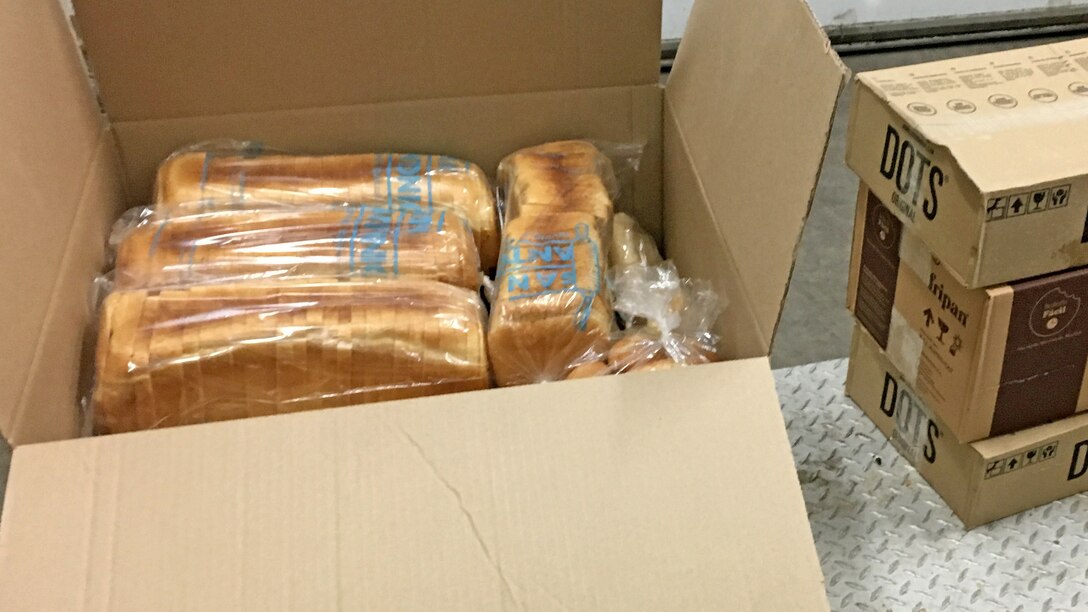 An open box shows plastic-wrapped loaves of sandwich bread