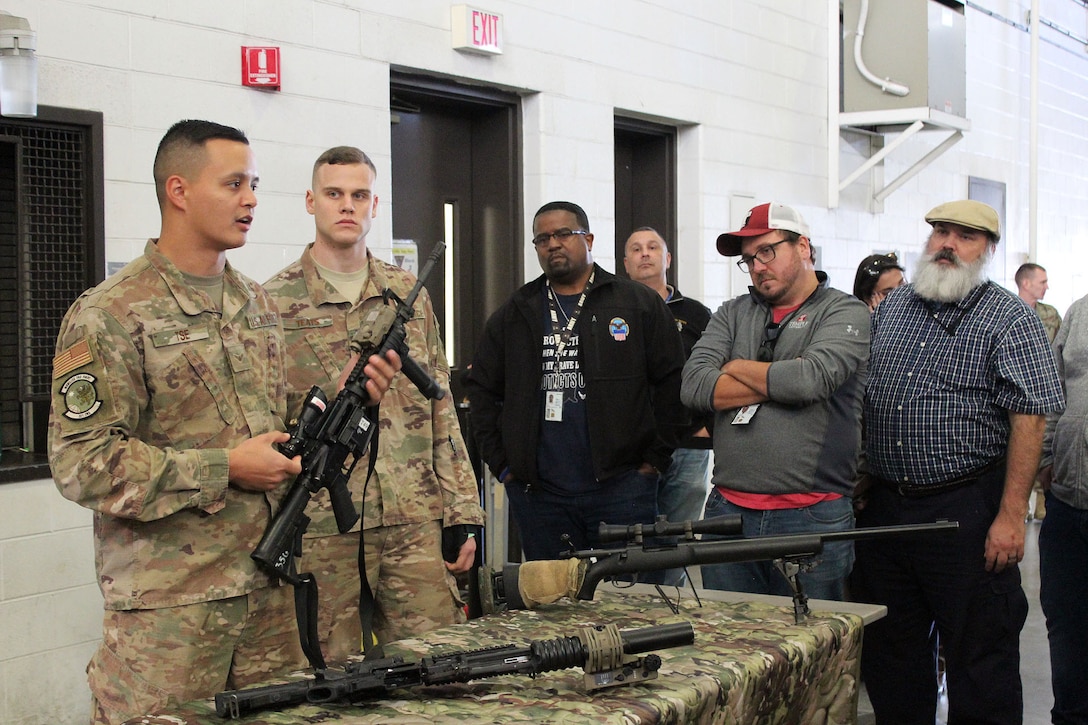 Air Force Airmen show examples of weapons during a tour of the Joint Base McGuire-Dix-Lakehurst in New Jersey during the Defense Logistics Agency Troop Support Academy, held Oct. 22-24. The visit gave new DLA Troop Support employees the opportunity to get a hands-on view of how logistics supports the warfighter.  (Photo by Nancy Benecki)