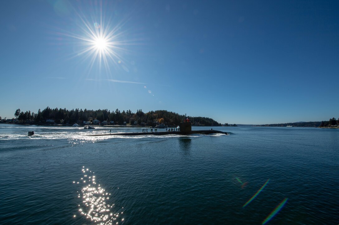 A submarine transits through the water on a bright sunlit day.