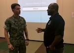 A person in a Marine uniform talks with a Civilian employee.