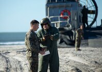 A U.S. Marine 2nd Marine Logistics Group, speaks with a Sailor from Landing Craft, Air Cushion (LCAC) 69 and 53, assigned to Assault Craft Unit (ACU) 4, during Type Commander Amphibious Training (TCAT) 20.1 on Onslow Beach, Camp Lejeune, North Carolina, Oct. 21-26, 2019. TCAT is a mobility exercise ashore in order to gain the requisite skills and experience to integrate with the U.S. Navy in follow on exercises and real-world operations.