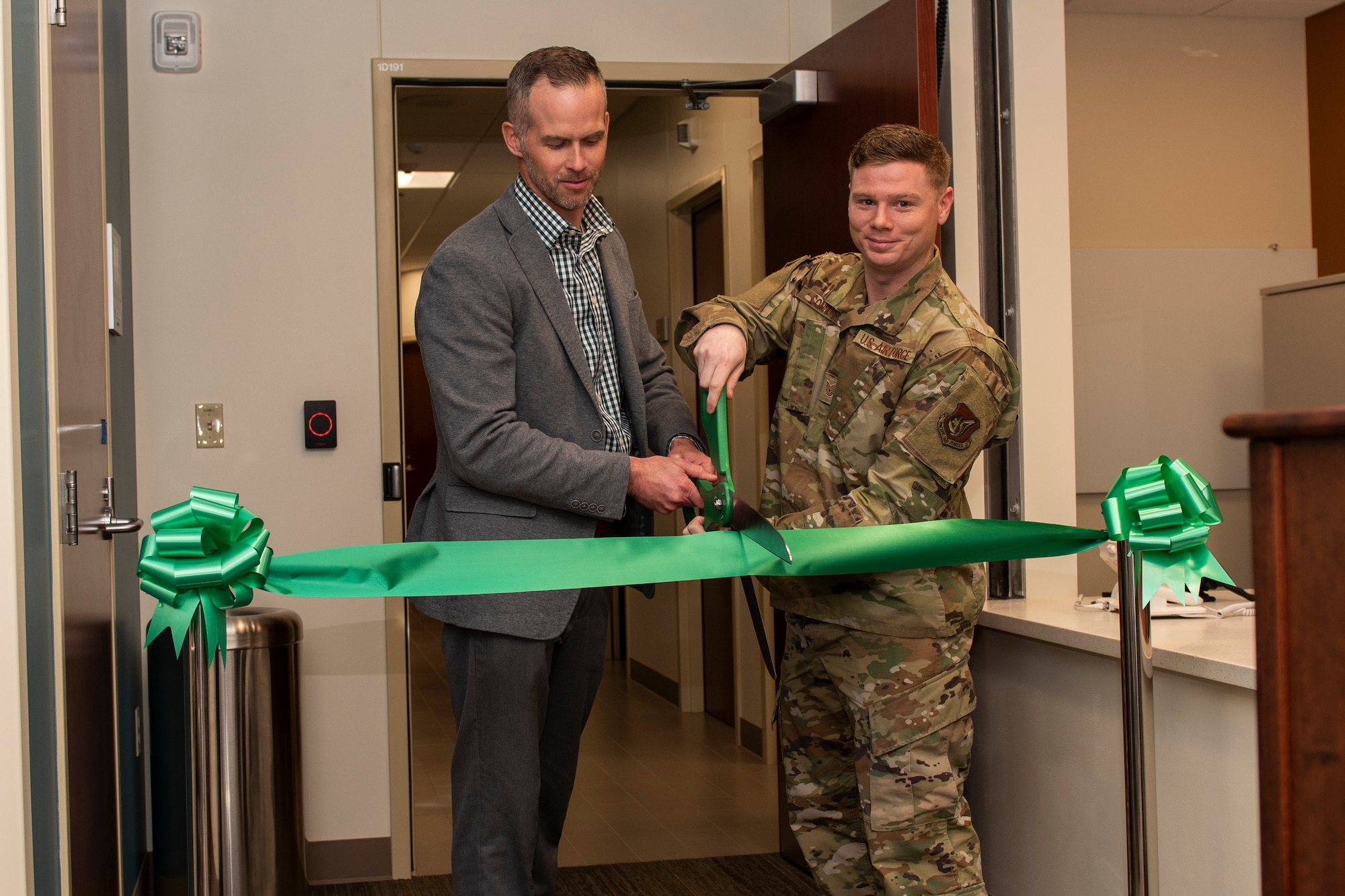 Matt Clugston (left), federal healthcare program manager with Walsh Construction, and U.S. Air Force Tech. Sgt. Sean Connors, 673d Surgical Operations Squadron MRI technologist, cut the ribbon at a ribbon-cutting ceremony for the new MRI suite in the Joint Base Elmendorf-Richardson hospital on JBER, Alaska, Oct. 28, 2019. The MRI area remodel included the creation of one joint control room, rather than the former two control rooms in separate areas; an upgraded 1.5 Tesla GE scanner; and newer patient amenities such as dressing rooms, a reception desk, a waiting area, and murals and lighting in the scanner rooms for patient comfort.