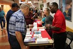 U.S. Air Force Capt. Derrick Wells, executive officer, Department of Medicine, Brooke Army Medical Center (right) hands out information brochures to patrons during Joint Base San Antonio’s Military Retiree Appreciation Day Oct. 19, hosted by BAMC.