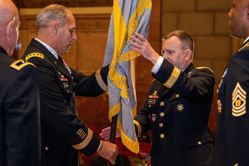 Gen. Gustave F. Perna, U.S. Army Materiel Command commanding general, center left, passes the U.S. Army Financial Management Command colors to Brig. Gen. Mark S. Bennett, USAFMCOM commanding general, during a ceremony at the Indiana War Memorial in Indianapolis, Oct. 25, 2019. Bennett took command from Maj. Gen. David C. Coburn, far left, and will work with Command Sgt. Maj. Courtney M. Ross, USAFMCOM senior enlisted advisor, far right, to lead the command. (U.S. Army photo by Mark R. W. Orders-Woempner)