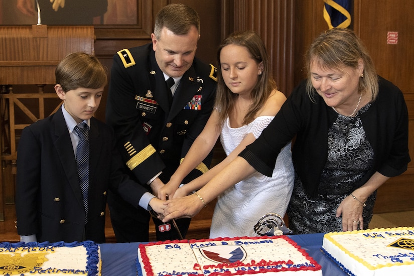 Brig. Gen. Mark S. Bennett, U.S. Army Financial Management Command commanding general, cuts a cake with his son, Matthew, his daughter, Allyson, and his wife, Yvonne shortly after he took command during a ceremony at the Indiana War Memorial in Indianapolis, Oct. 25, 2019. The cake was decorated with a U.S. Army Materiel Command patch symbolizing USAFMCOM’s move under AMC earlier that month. (U.S. Army photo by Mark R. W. Orders-Woempner)