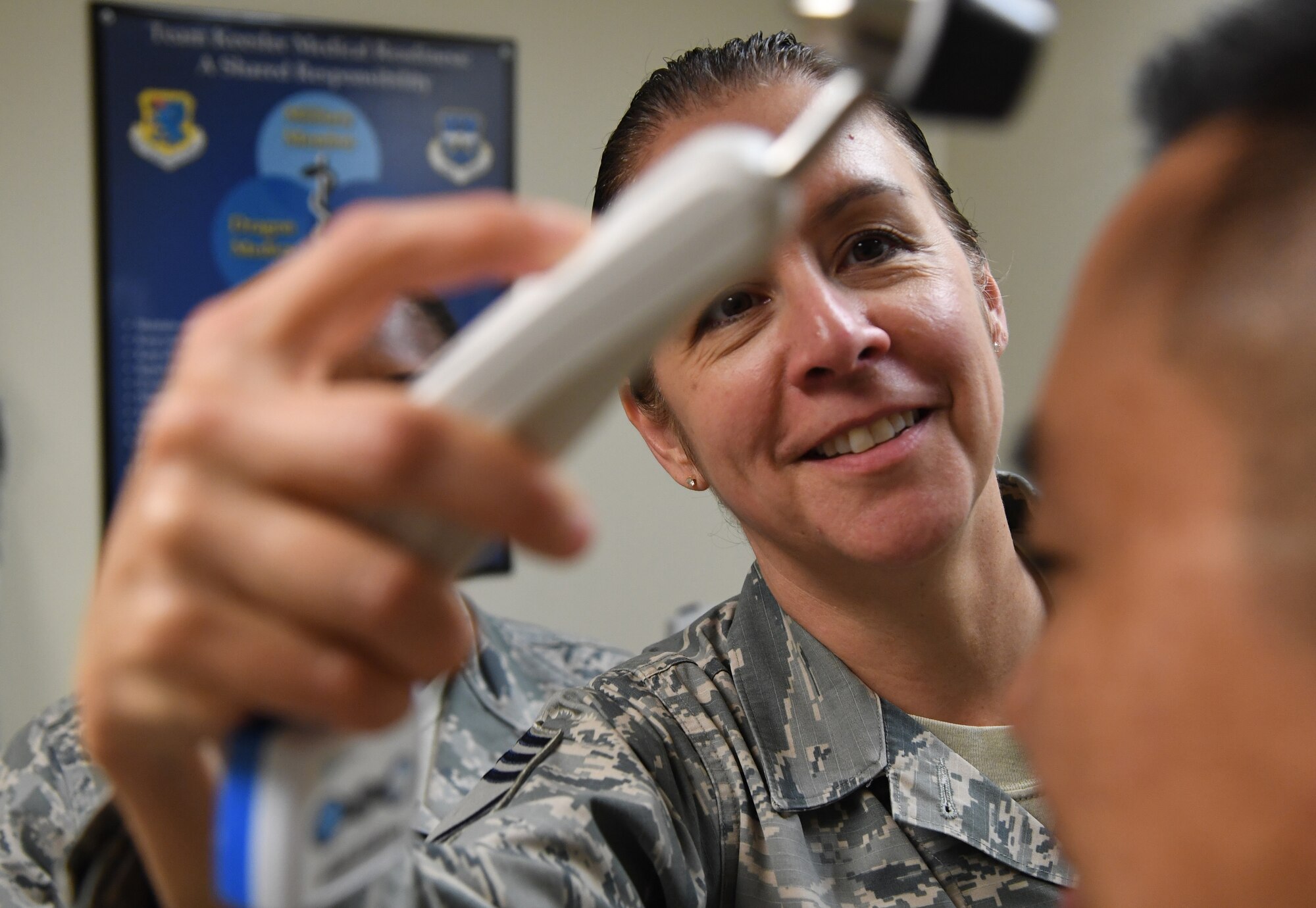 U.S. Air Force Chief Master Sgt. Paula Eischen, 81st Medical Group superintendent, checks a patient's temperature while visiting the Base Operation Medicine Cell inside the Keesler Medical Center at Keesler Air Force Base, Mississippi, Aug. 22, 2019. The "Dragon Medic Experience" allowed the 81st MDG leadership to work side-by-side with group medics in order to understand the challenges and barriers they may face while providing care. It also allowed them to see first-hand the great ideas that the staff has implemented to focus on the patient experience. This experience helps us cultivate an environment where senior leadership has direct engagement and connection with our front line medics who strive to deliver outstanding care. (U.S. Air Force photo by Kemberly Groue)