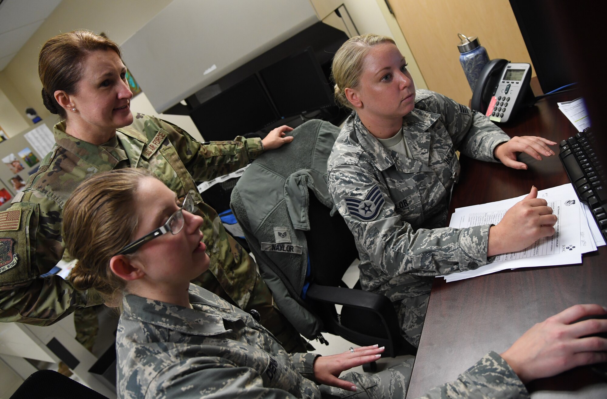 U.S. Air Force Staff Sgts. Ashley Dena and Hannah Naylor, 81st Aerospace Medicine Squadron medical technicians, brief Col. Beatrice Dolihite, 81st Medical Group commander, on the medical clearance process at the Base Operation Medicine Cell inside the Keesler Medical Center at Keesler Air Force Base, Mississippi, Aug. 22, 2019. The "Dragon Medic Experience" allowed the 81st MDG leadership to work side-by-side with group medics in order to understand the challenges and barriers they may face while providing care. It also allowed them to see first-hand the great ideas that the staff has implemented to focus on the patient experience. This experience helps us cultivate an environment where senior leadership has direct engagement and connection with our front line medics who strive to deliver outstanding care. (U.S. Air Force photo by Kemberly Groue)