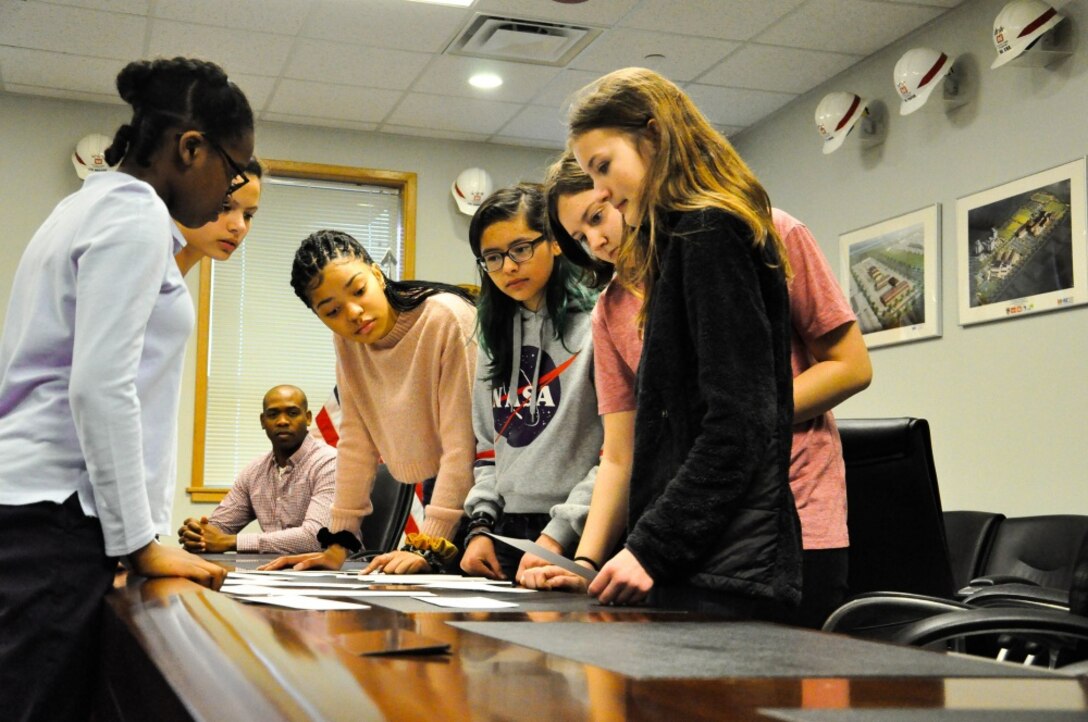 Middle school students study cards on a conference table.