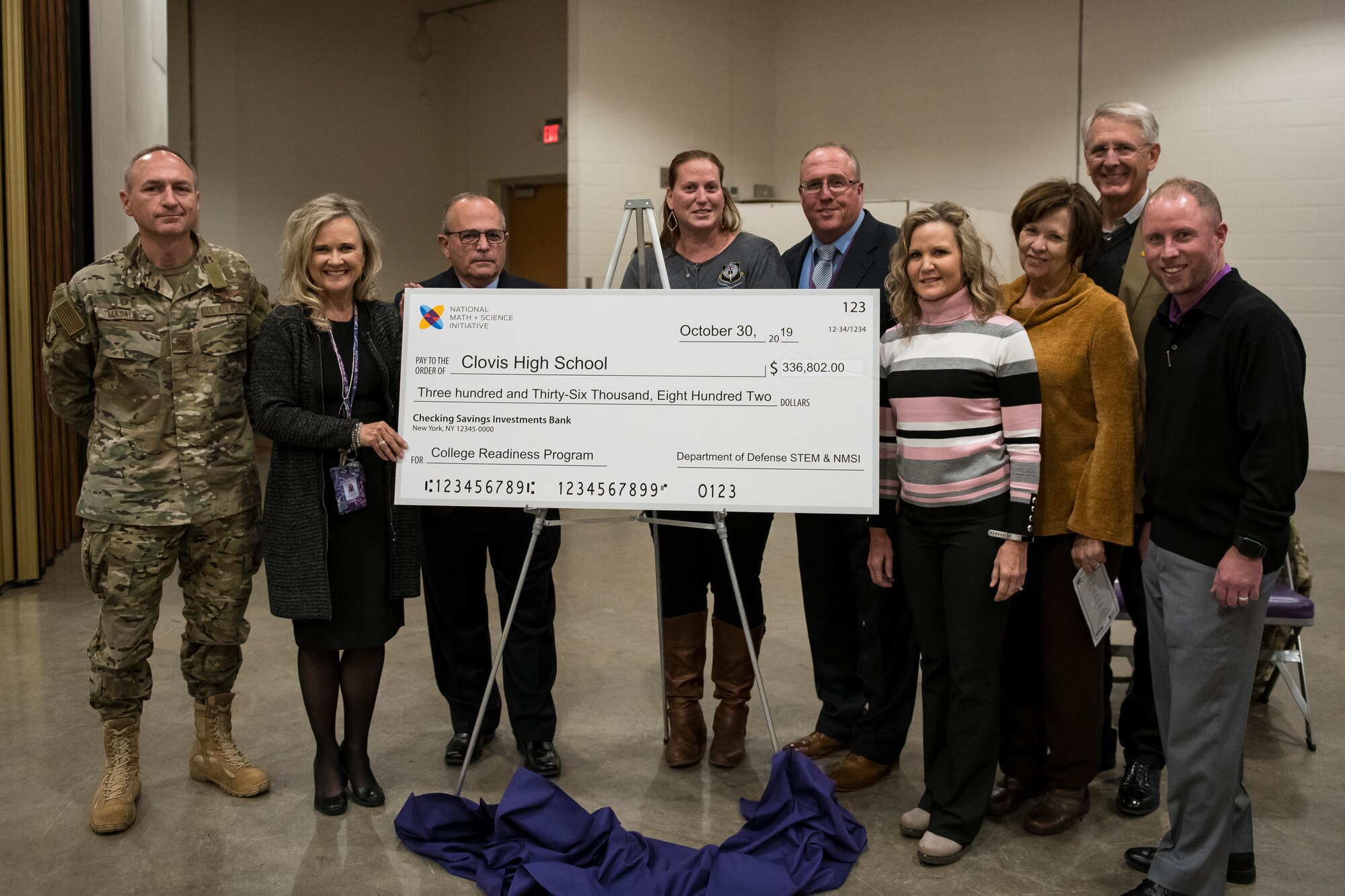 Members of Cannon Air Force Base and Clovis High School stand around the newly revealed check for the grant received at the National Math and Science Initiative program reveal at Clovis, N.M., Oct. 30, 2019. The event was held to announce the $336,000 grant that the Department of Defense will be providing Clovis High School for training, technology, and more to enhance the STEM and Advanced Placement® education opportunities for all students.  (U.S. Air Force photo by Senior Airman Vernon R. Walter)