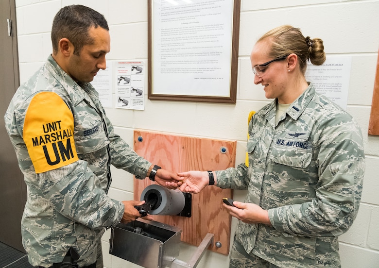 Tech. Sgt. Damien Seelbach, cybersecurity noncommissioned officer in charge, hands 1st Lt. Rachael Burks, cyber operations flight commander, a 9mm bullet from the chamber of a Beretta M9 during the disarming process conducted in the 436th Communications Squadron's arming area, Oct. 24, 2019, on Dover Air Force Base, Del. Both Seelbach and Burks are squadron Unit Marshals. (U.S. Air Force photo by Roland Balik)