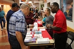 U.S. Air Force Capt. Derrick Wells, executive officer, Department of Medicine, Brooke Army Medical Center (right) hands out information brochures to patrons during Joint Base San Antonio’s Military Retiree Appreciation Day Oct. 19, hosted by BAMC.