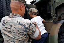 海兵隊の大型トラックに乗り込もうとする児童に手を差し伸べる海兵隊員。沖縄県浦添市にある米軍基地で10月26～27日、フェスティバルが開催され、約23000人の日米の観客が会場に足を運びました。