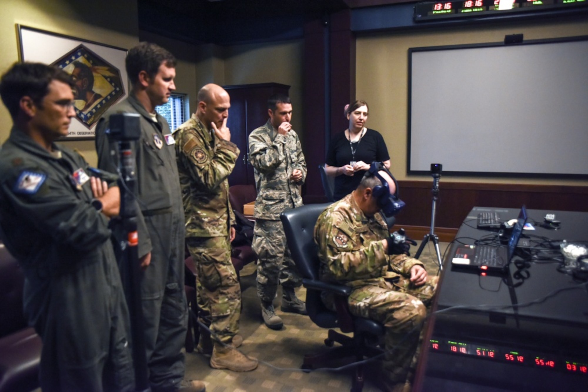 Members of AFWERX and the 189th Airlift Wing Innovation Team watch as Col. Dean Martin, 189th AW commander, tests the virtual reality headset and haptic glove designed to streamline training. (U.S. Air National Guard photo by Master. Sgt. Jessica Roles)