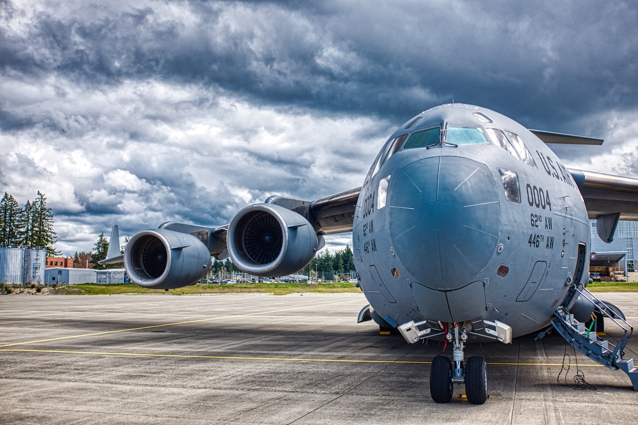 An aircraft sits on a concrete slab. The sky is cloudy and gray.