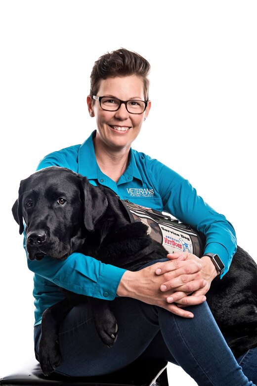 Stacy Pearsall sitting with service dog Charlie on her lap.
