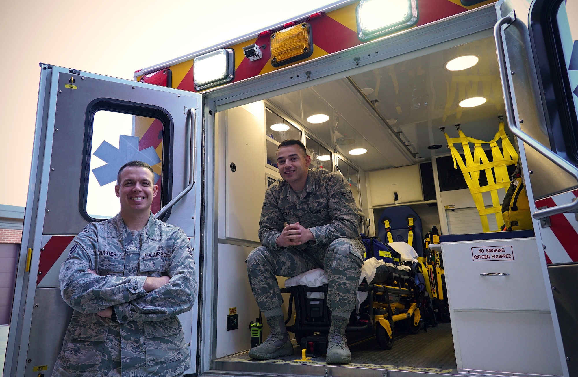 Ambulance service technicians with the 319th Medical Group, Staff Sgt. Jocelin Cartier, left, and Airman 1st Class Michael Nolan, pose for a photo on National First Responders Day, Oct. 28, 2019, on Grand Forks Air Force Base, North Dakota. Cartier and Nolan have served a collective six years in the Air Force, and say they enjoy being able to help people when needed. (U.S Air Force photo illustration by Senior Airman Elora J. Martinez)(This image was emphasized using color filters and vignette.)